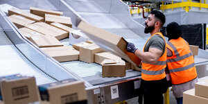 Mitarbeiter des Paketversenders Amazon sortieren Pakete im Sortierzentrum