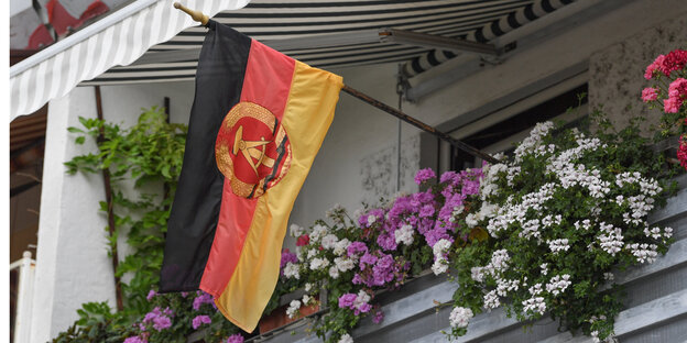 DDR-Fahne weht an Balkon mit Blumendekoration