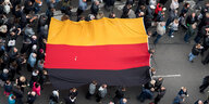 Teilnehmer einer Demonstration tragen eine Deutschlandfahne