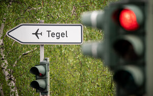 Ein Schild weist an einer Roten Ampel zum Flughafen Tegel – der Flughafen soll schließen