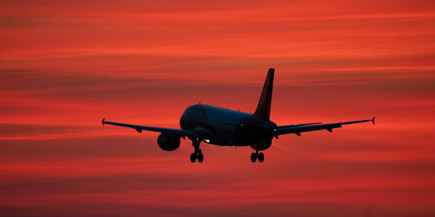 Ein Flugzeug vor rotem Himmel.