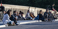 Menschen sitzen am Abend auf der Friedrichsbrücke in Berlin-Mitte und genießen das Licht der untergehenden Sonne