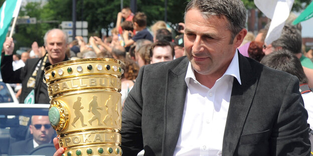 Klaus Allofs hält den DFB-Pokal.