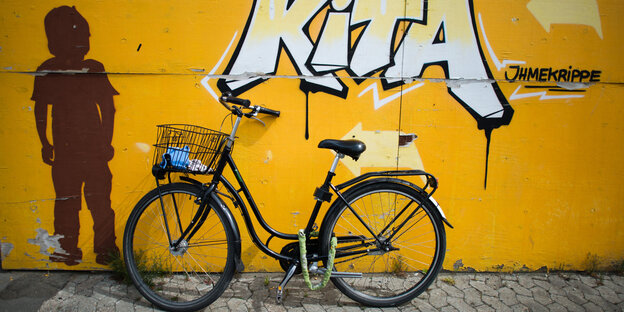 Ein Fahrrad lehnt an einer Wand des Ihmezentrums in Hannover. Darüber ein Grafitti "Kita".