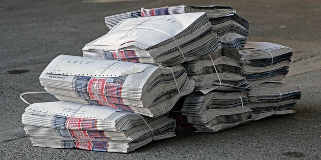 Verschnürte Zeitungsstapel liegen am Strassenrand