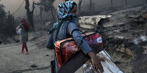 Eine Frau flüchtet mit ihren Taschen beladen aus dem brennenden Lager Moria