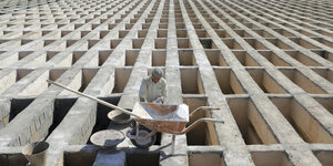 Ein Mann arbeitet an noch leeren Gräbern aus Zement und Stein ih Teheran.