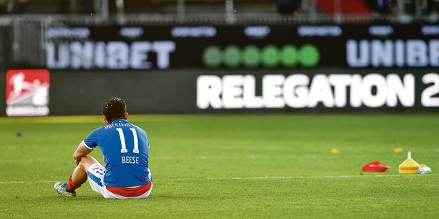 Kiels Stürmer Fabian Reese sitzt nach dem verlorenen Relegationsspiel gegen Köln enttäuscht auf dem Rasen.