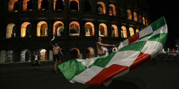 Ein Fan schwekt eine riesige Italienfahne vor dem Kolosseum in Rom
