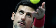 Novak Djokovic wirft einen Tennisball hoch und schaut ihn an