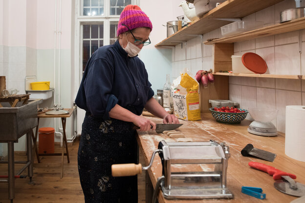 Eine Frau steht in einer Küche und schneidet Pastateig.