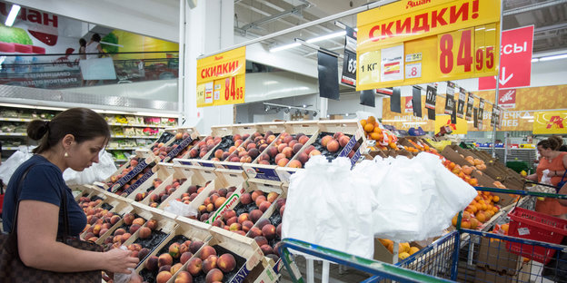 Eine Frau vor Regalen voller Pfirsiche in einem Supermarkt
