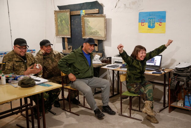 3 ukrainische Soldaten, eine Soldatin sitzen auf Bänken in einem Raum, schauen in eine Richtung, freuen sich