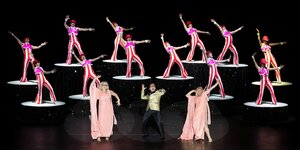Das farbenfroh kostümierte Revue-Ensemble vollführt in der Komischen Oper Berlin eine Choreographie.