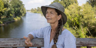 Frauke Bennett steht mit Hut auf einer Brücke über den Oder Podern, sie hat einen langen Zopf