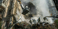 Feuerwehrleute löschen ein durch Bomben zerstörtes Hochhaus