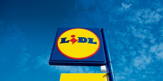 Ein Schild mit "Lidl"-Logo vor einem blauen Himmel.