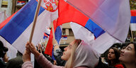 Menschen halten bei einer Protestaktion in Kosovo serbische Flaggen