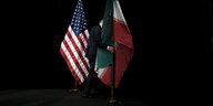 Eine Person zwischen einer Fahne der USA und einer Fahne des Iran