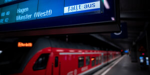 Ein roter Zug steht an einem Bahngleis, auf der Abfahrtsanzeige darüber steht "Zug fällt aus".