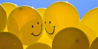 Gelbe Luftballons mit Smileys in blauen Himmel