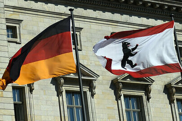 Auf der linken Seite weht die Deutschlandflagge im Wind, rechts daneben die Flagge vom Land Berlin, beide sind vor dem Abgeordnetenhaus zu sehen.
