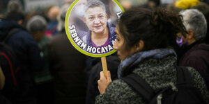 Eine Frau hält ein Schild in der Hand, darauf abgebildet ist Şebnem Korur Fincancı