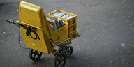 Ein Trolley eines Zustellers der Deutschen Post steht auf der Straße