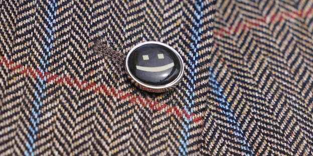 Ein Smiley steckt als Logo des Clubs der Optimisten an einem Sakko.