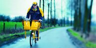 Briefträger fährt auf einer Landstraße mit dem Fahrrad