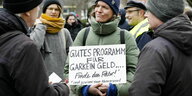 Eine Frau hält ein Plakat "Gutes Programm für Garkein Geld...Finde den Fehler! und gewinne einen Massagesessel