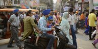 Eine indische Sikh-Familie - Vater, Mutter und zwei Söhne - fahren auf einem Motorrollder durch Amritsars Verkehrsgewühl