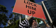 Ein Mann hält ein Schild hoch: "Lock him up"