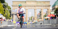 Radsportlerin Ella Curtis aus Großbritannien fährt vor dem Brandenburger Tor ins Ziel ein