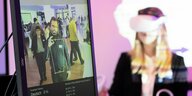 Eine Frau mit einer Virtual-Reality-Brille neben einem Bildschirm