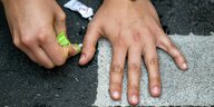 Die Hand einer Klimaaktivistin der Gruppe «letzte Generation» klebt auf einer Straße.