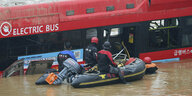 Ein Bus, umgeben von Wasser, davor ein Schlauchboot mit Rettungskräften