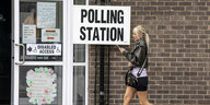 Frau vor Wahllokal mit Aufschrift "Polling Station"