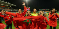 Die Frauen-Nationalmannschaft von Marokko feiert und hält eine Fahne in der Hand