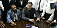 Ex-Premier Khan an einem Tisch sitzend, umgeben von Gefolgsmännern