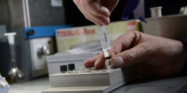In einem Labor wird eine Flüssigkeit aus einem Röhrchen mit einer Spritze aufgenommen