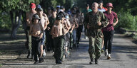Kinder und Jugendliche in Militäruniformen laufen auf einer Straße