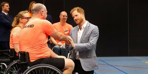 Prinz Harry geht in die Knie, um einem Rollstuhlfahrer die Hand zu geben