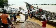 Boote liegen am Ufer den Nigers und werden entladen. Die Waren sind vor allem in hellen Säcken verpackt