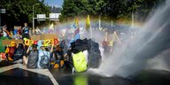 Ein Wasserwerfer greift eine Reihe von Aktivisten an, die auf der Straße sitzen