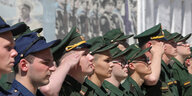 Junge russische Männer in Uniform stehen salutierend in einer Reihe
