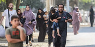 Palästinensische Familien laufen im eiligen Schritt auf einer Straße