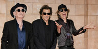 Keith Richards, Ronnie Wood und Mick Jagger stehen vor einer Wand