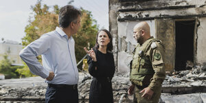 Außenministerin Baerbock und Außenminister Cohen vor einem zerstörten Haus.