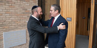 Der Rabbi Eli Levin mit Kippa auf dem Kopf tätschelt vor dem Eingang der Synagoge die Schulter von Labourchef Starmer.
